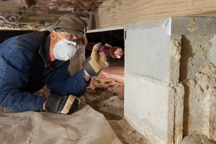 Pest technician inspecting a crawl space in Houston TX home